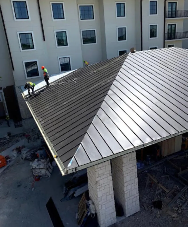 Crew installing standing seam metal roof panels on a commercial project in Bessemer City